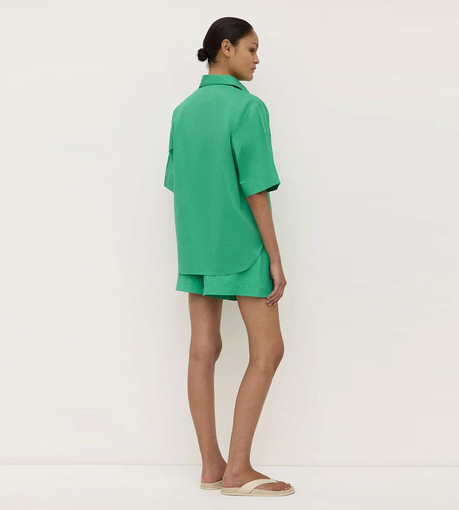Person wearing a green outfit standing against a white background