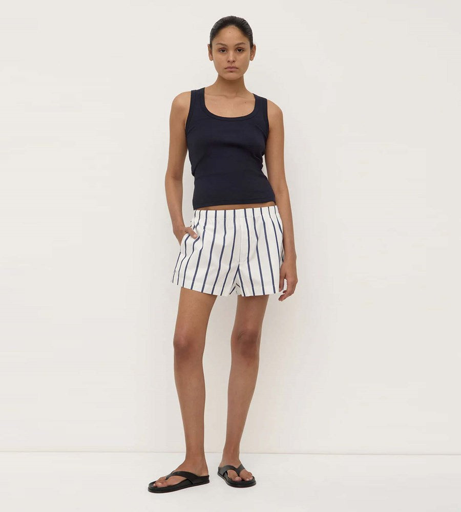 Woman wearing a navy tank top and striped shorts on a white background