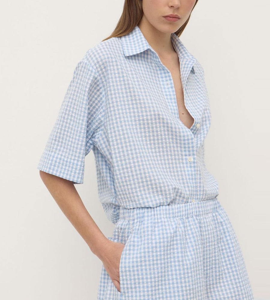 Person wearing a blue and white checkered outfit against a plain background