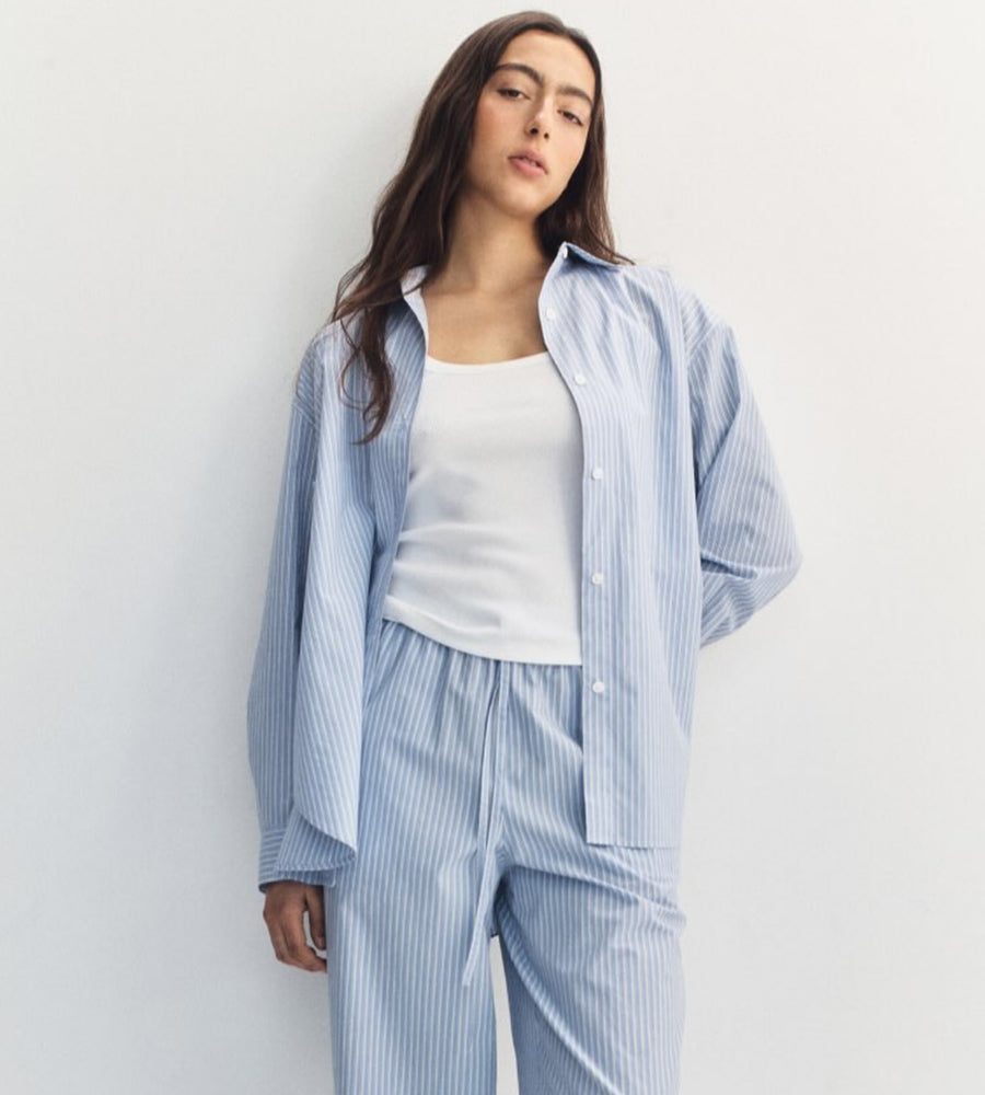 Woman wearing a light blue striped pajama set against a white background