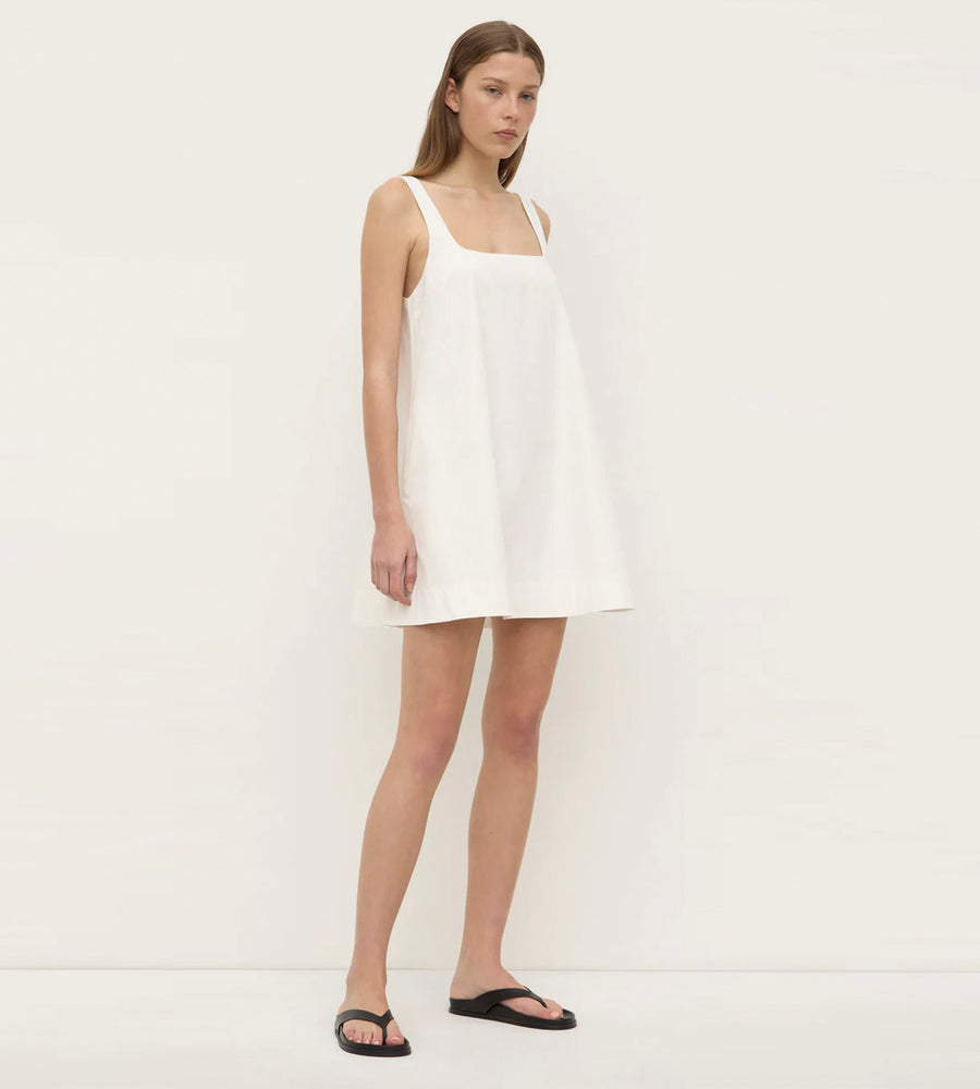 Woman wearing a white sleeveless dress on a plain background
