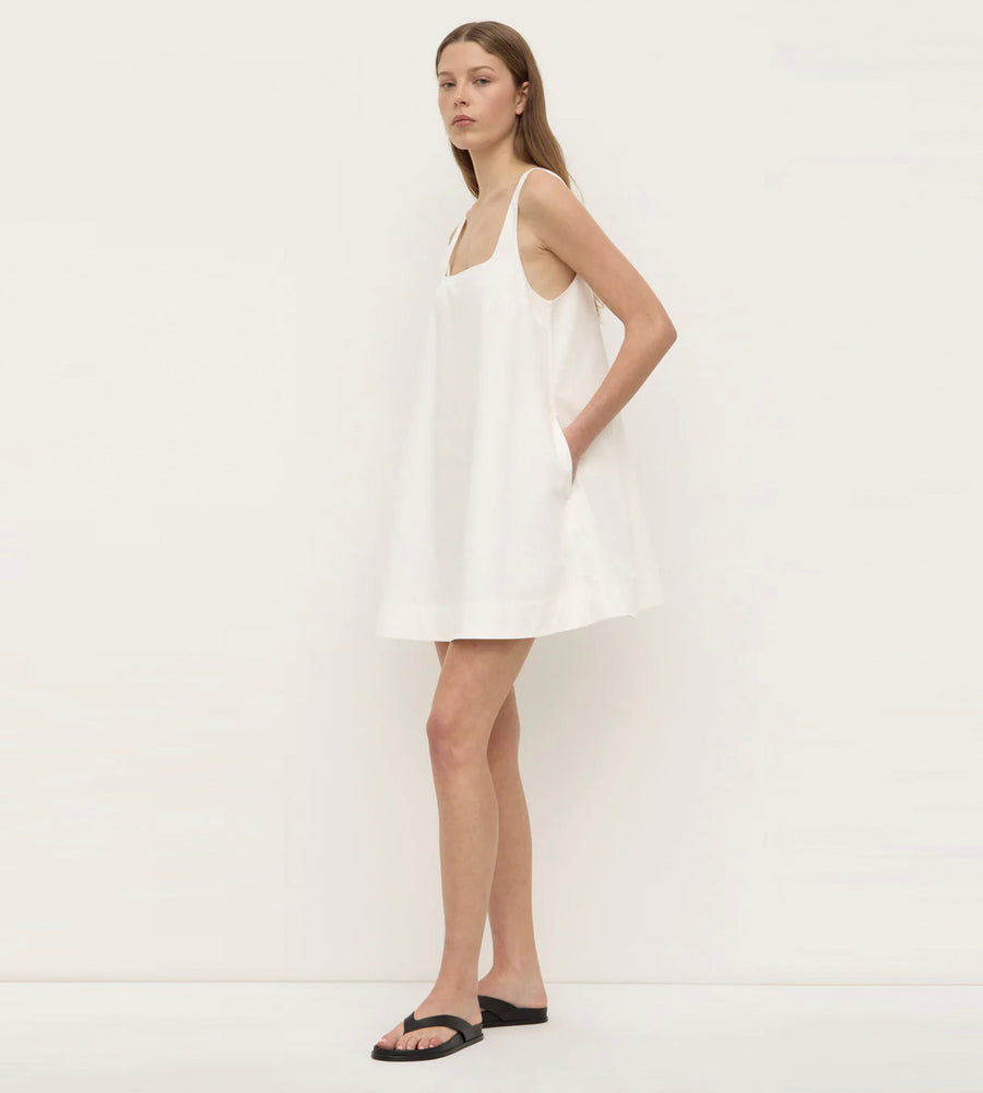 Woman wearing a white dress against a plain background