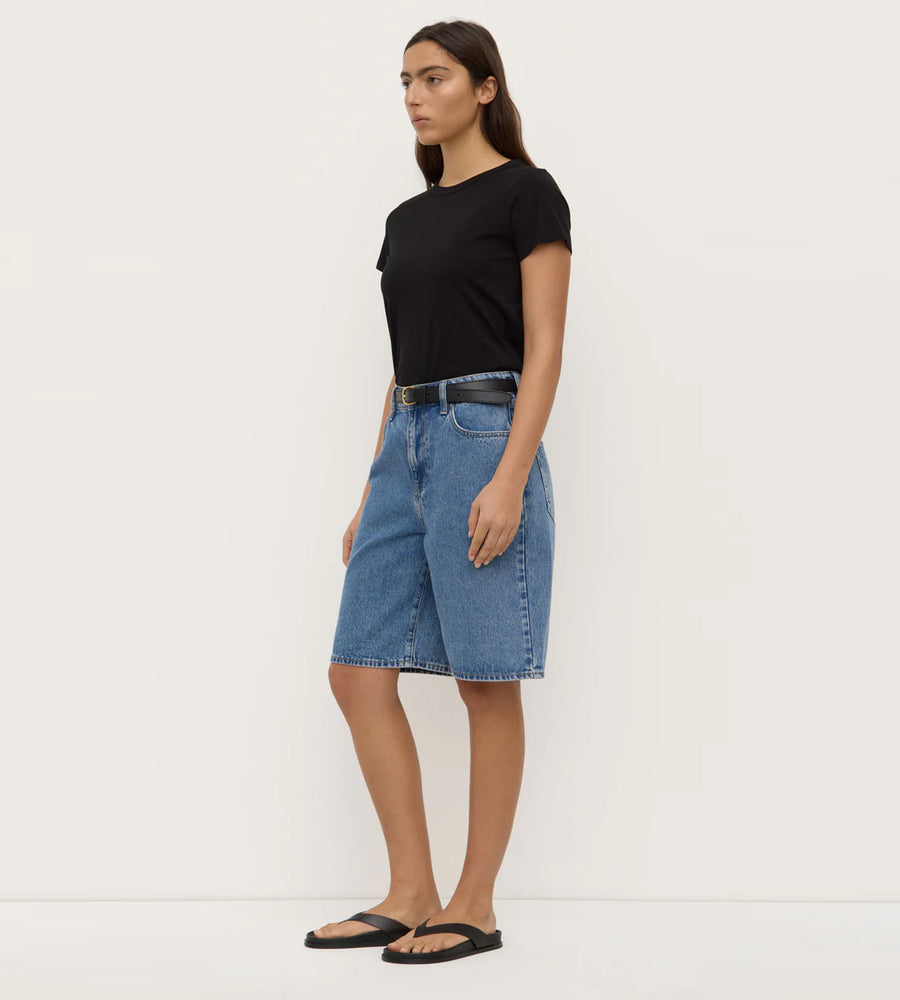Woman wearing a black t-shirt and blue denim skirt on a white background