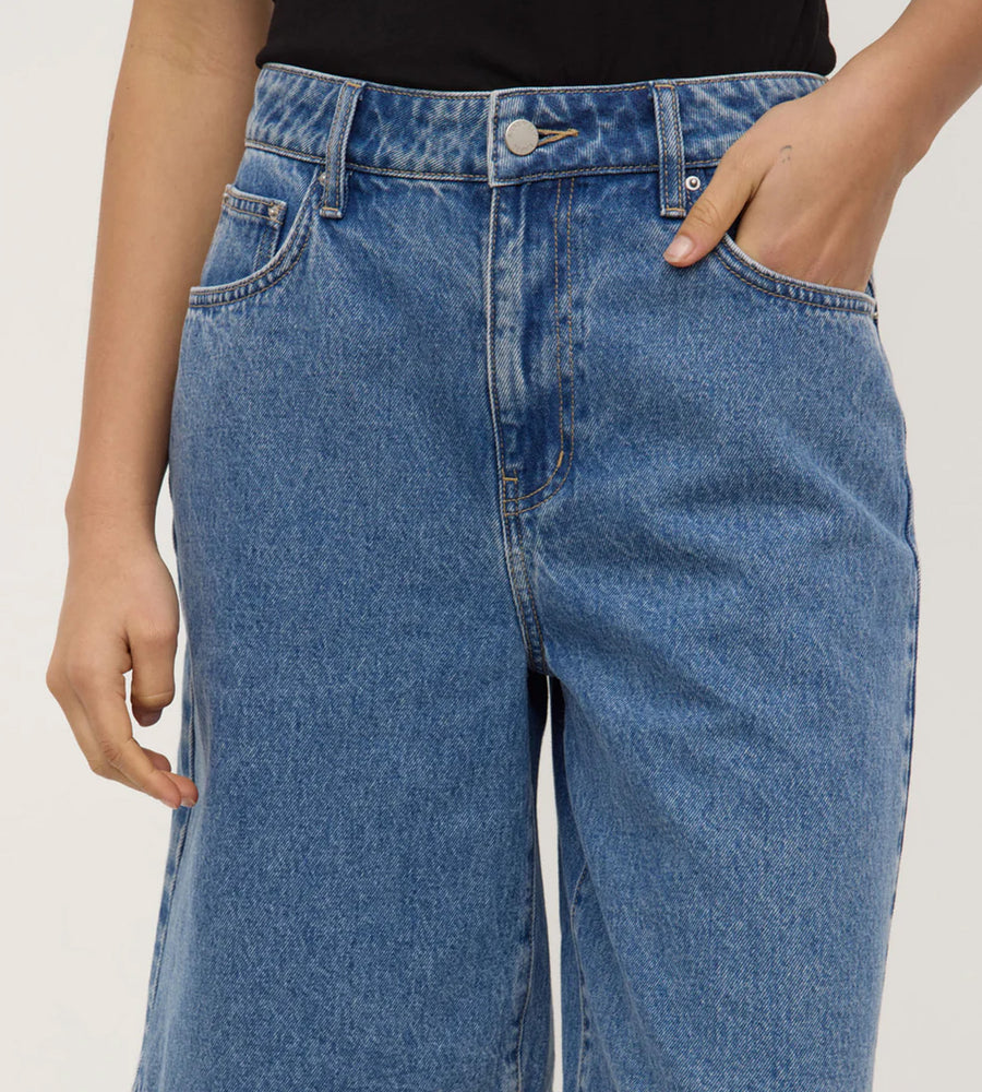 Person wearing blue jeans on a plain background
