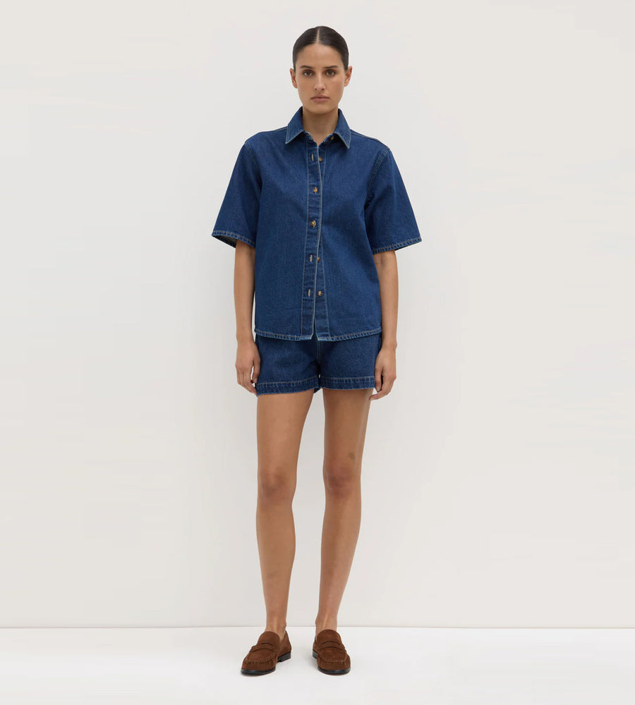 Woman wearing a blue denim shirt and shorts on a white background