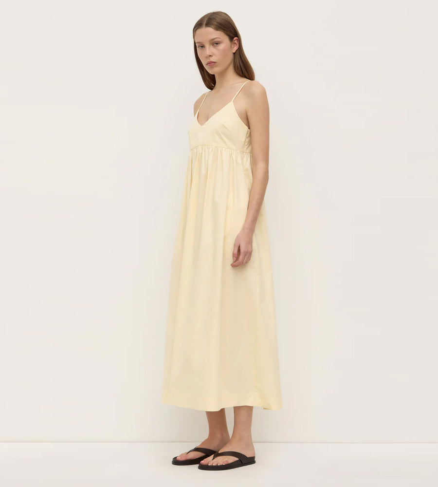 Woman wearing a light yellow slip dress against a white background