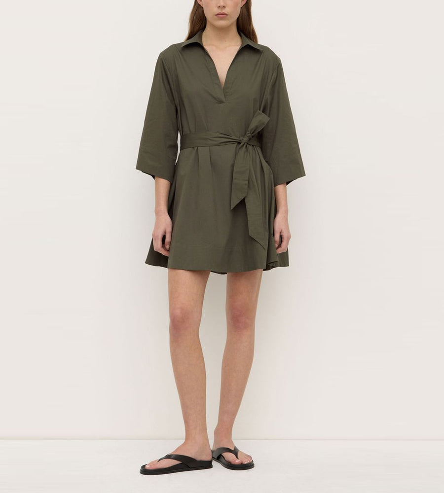 Person wearing a green dress with a belt on a white background