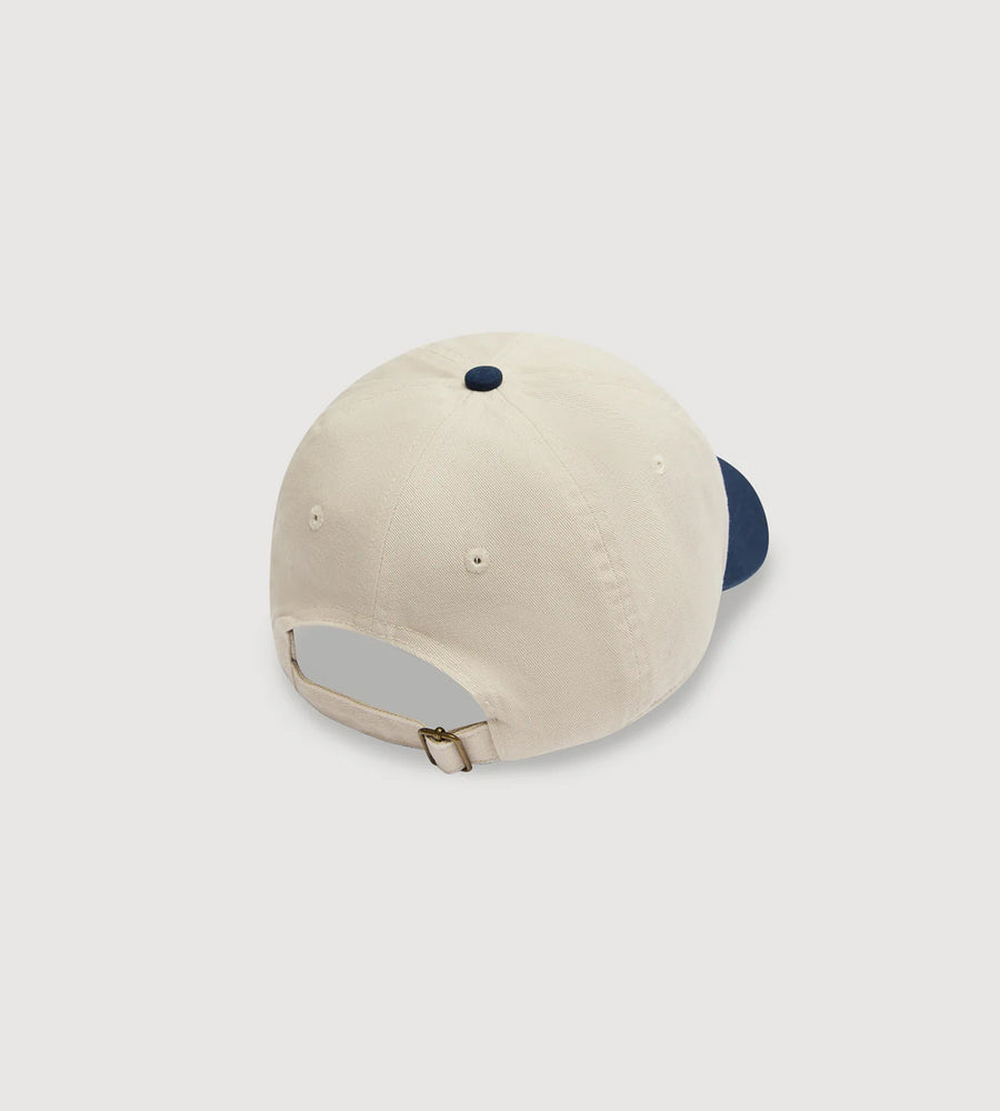 Beige and navy baseball cap on a light gray background