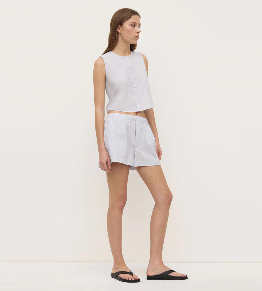 Woman wearing a light gray sleeveless top and shorts on a white background