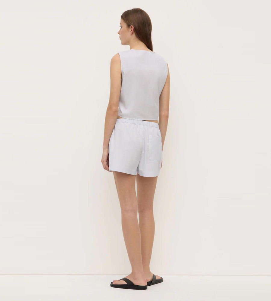 Woman wearing a light gray sleeveless top and shorts on a white background