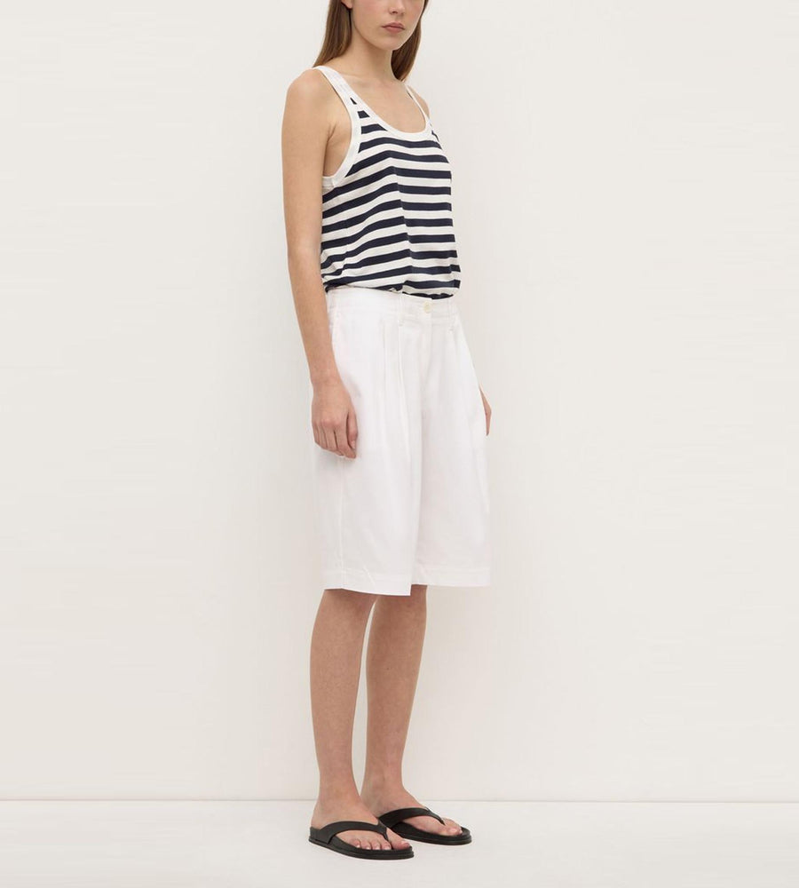 Person wearing a black and white striped tank top and white skirt on a plain background