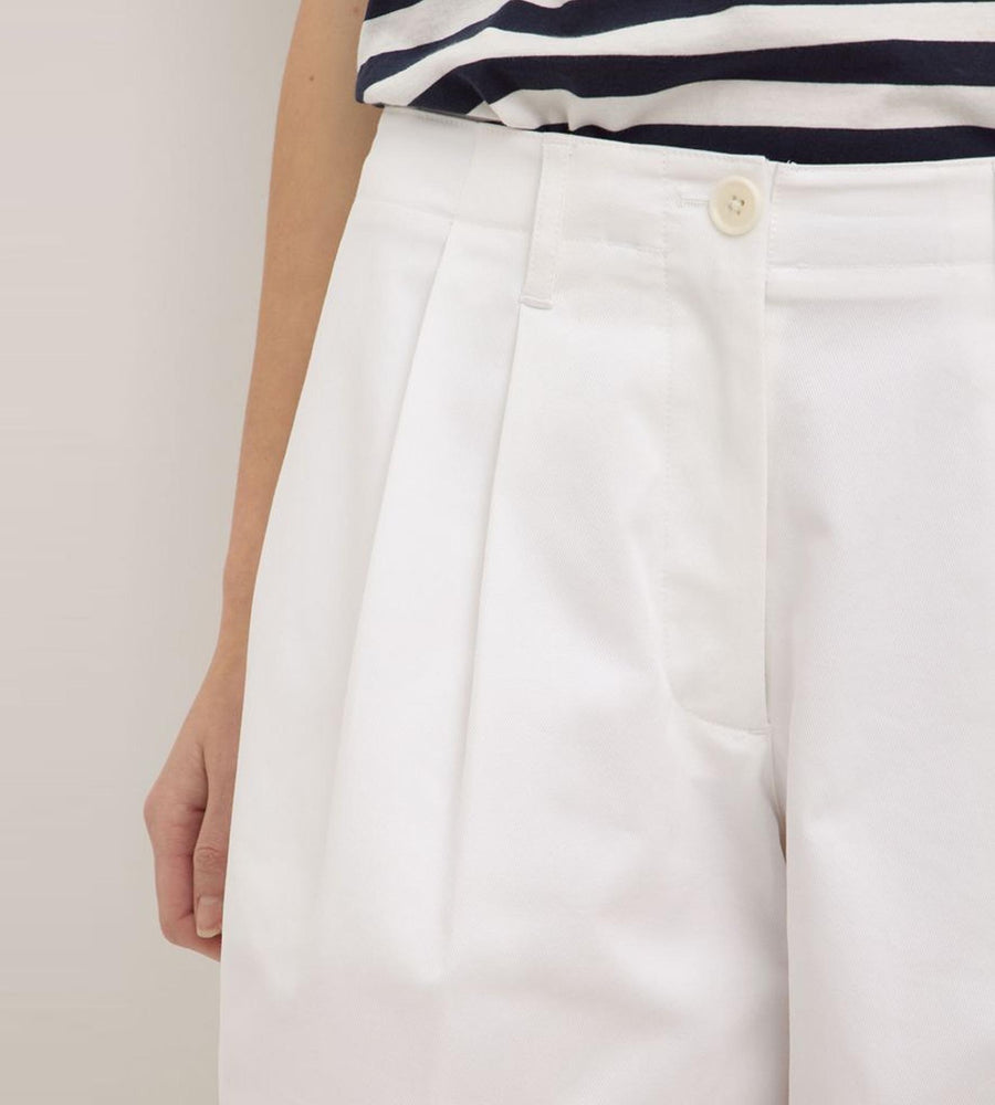 White pants with a striped shirt on a neutral background
