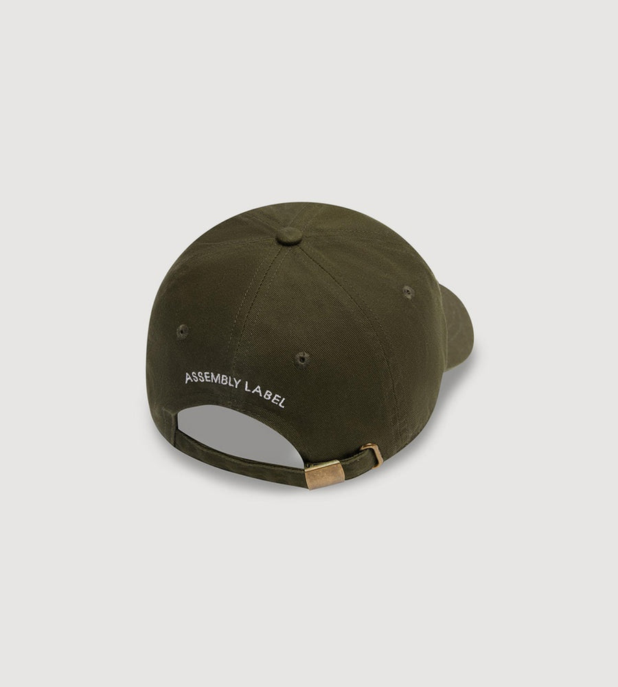 Green cap with 'Assembly Label' branding on a light gray background
