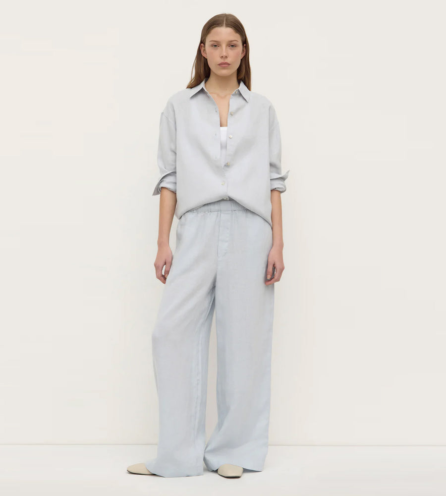 Woman wearing a light blue shirt and pants on a white background