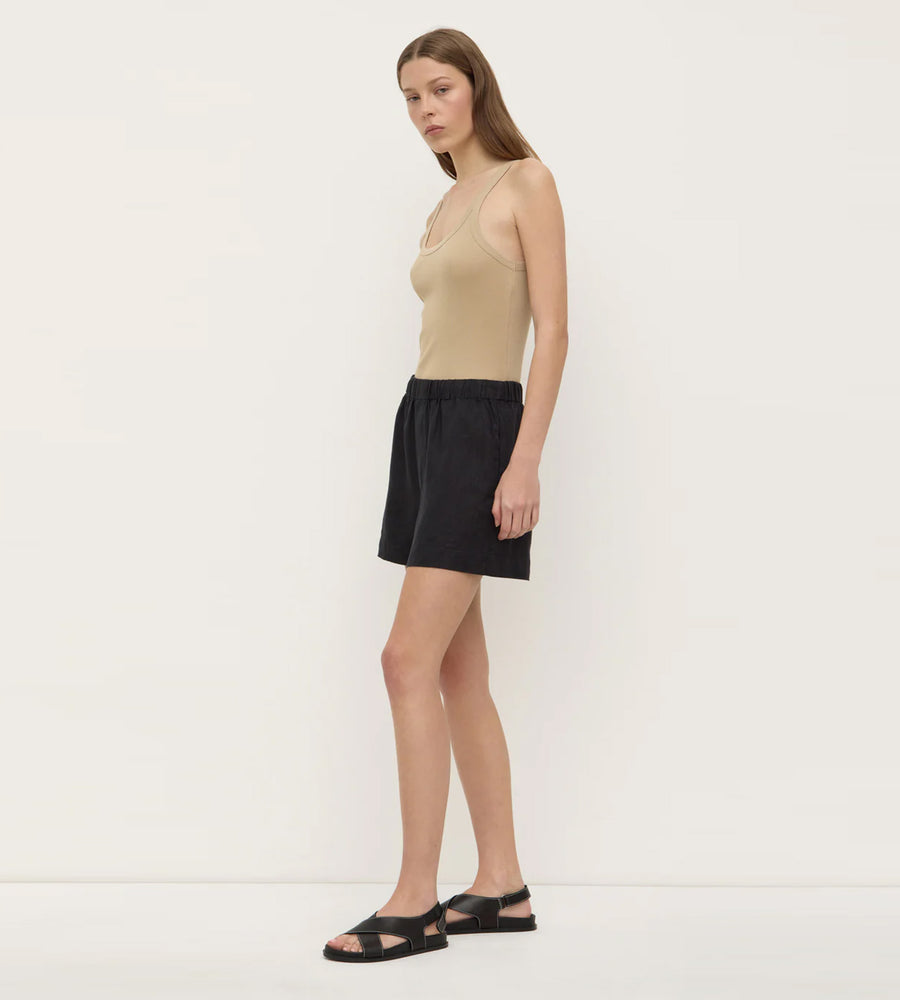 Woman wearing a beige tank top and black skirt on a white background