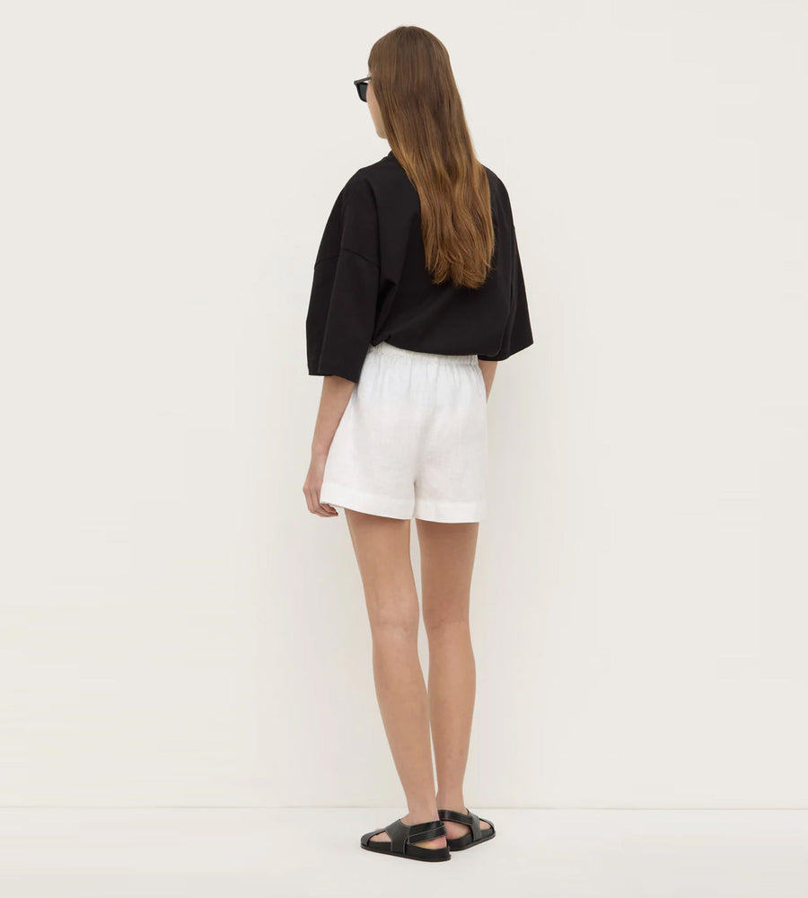 Person wearing a black top and white shorts on a plain background