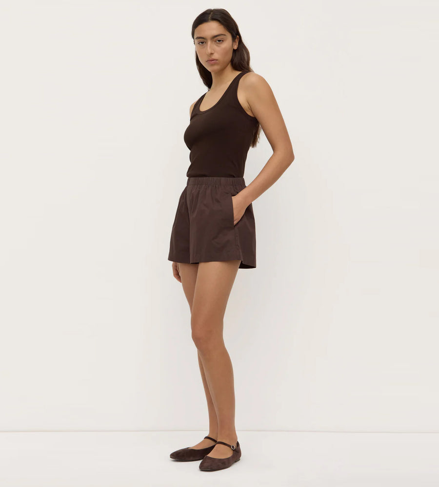 Woman wearing a brown sleeveless top and shorts on a white background