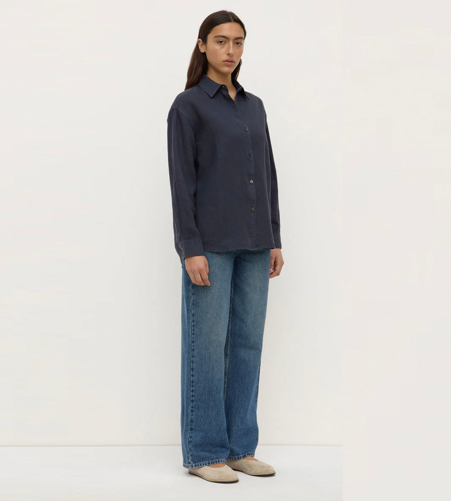 Person wearing a dark shirt and blue jeans on a white background