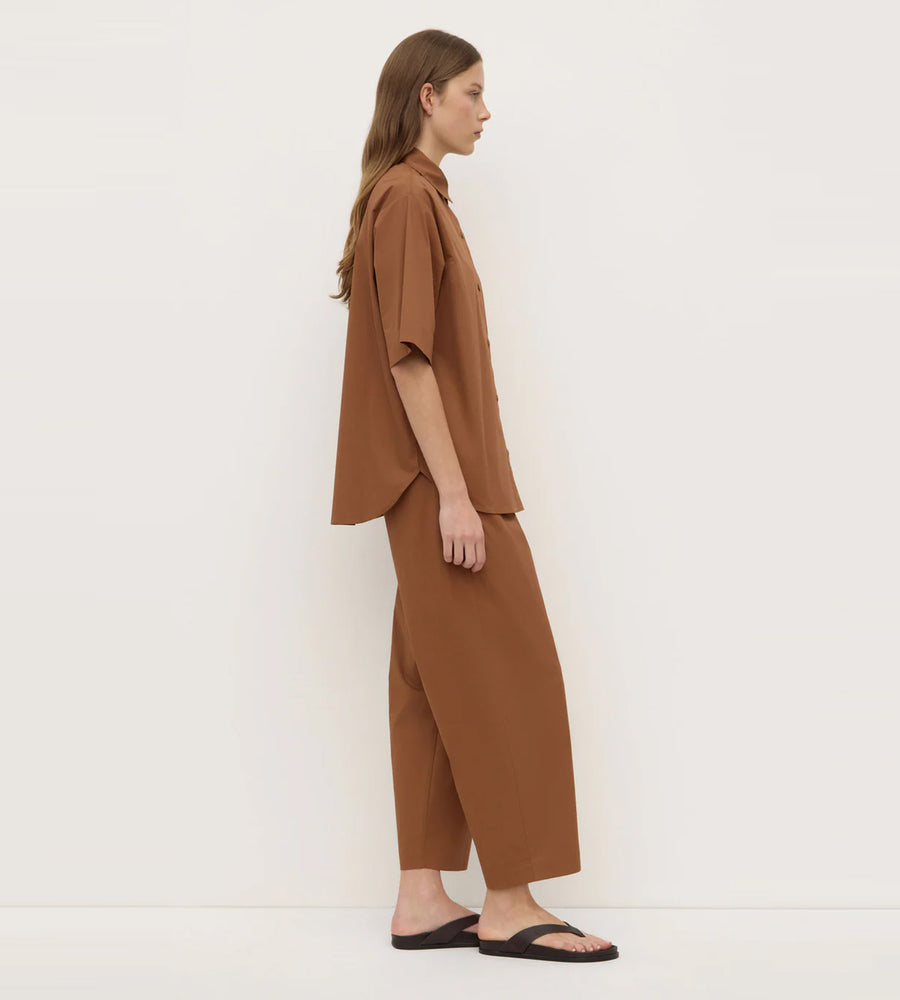 Woman wearing a brown outfit standing against a white background