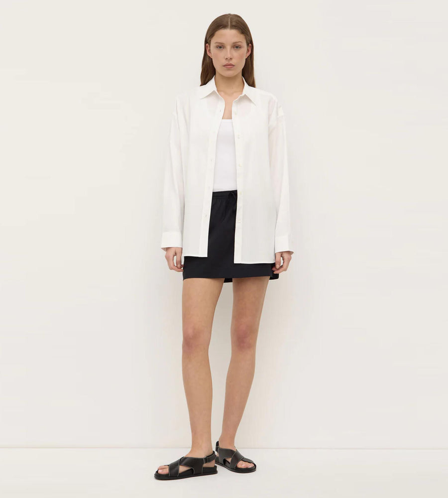Woman wearing a white shirt and black shorts against a plain background