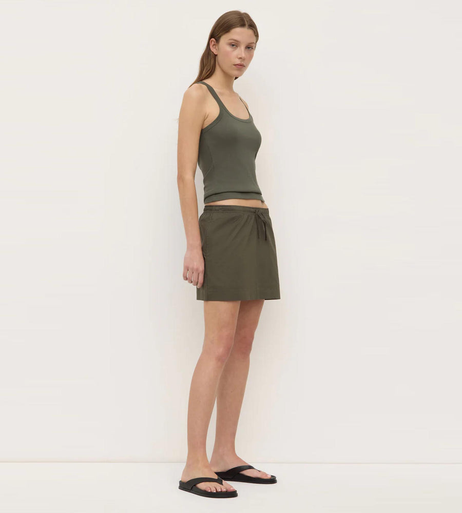 Woman wearing a green tank top and skirt on a white background