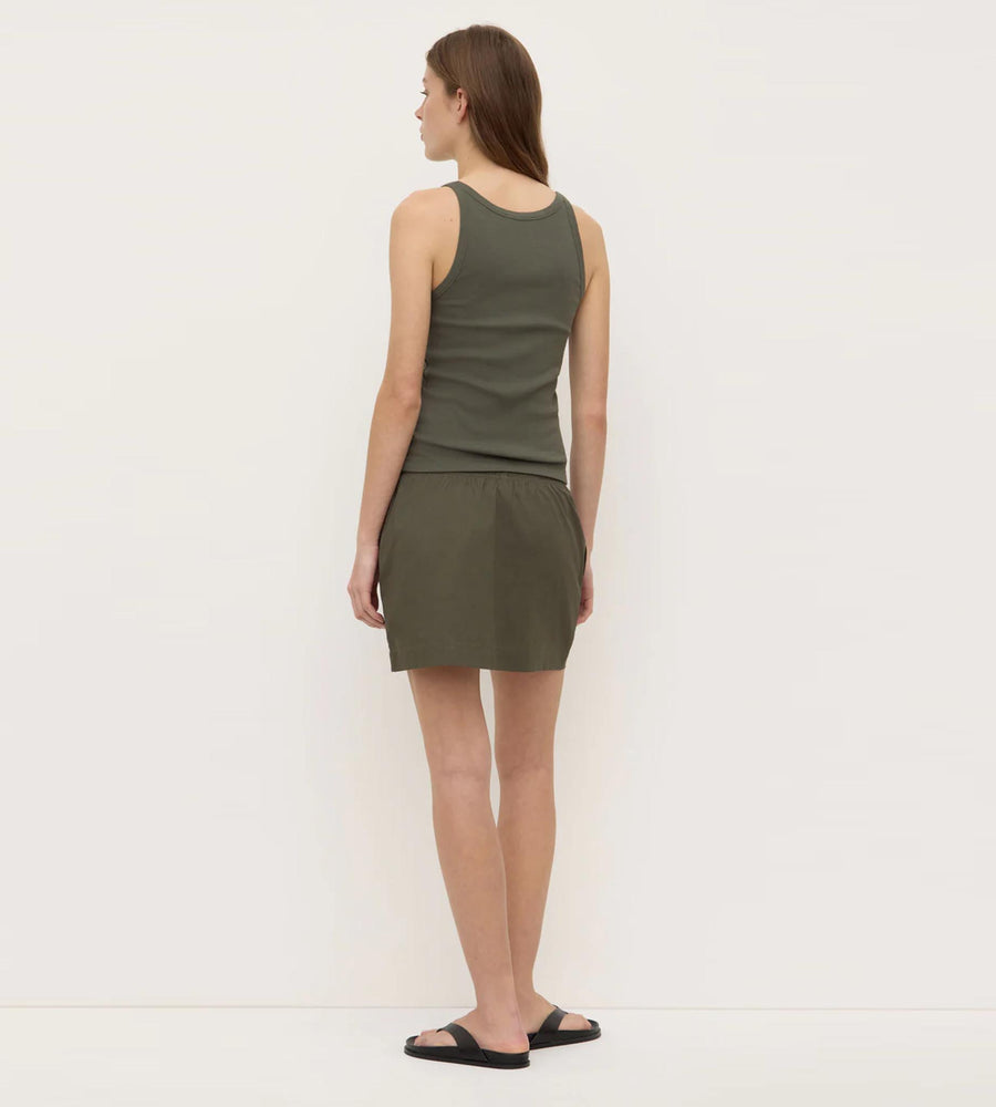 Woman wearing a green sleeveless top and skirt set on a white background