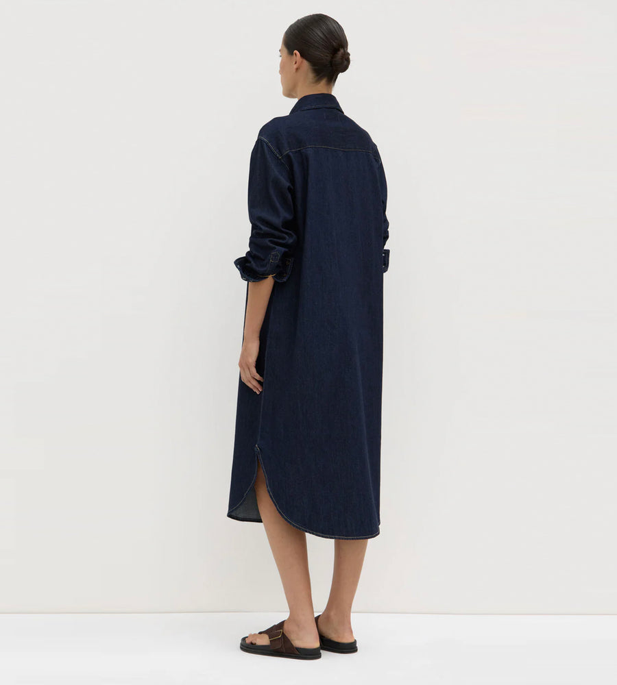 Woman wearing a long navy dress against a white background
