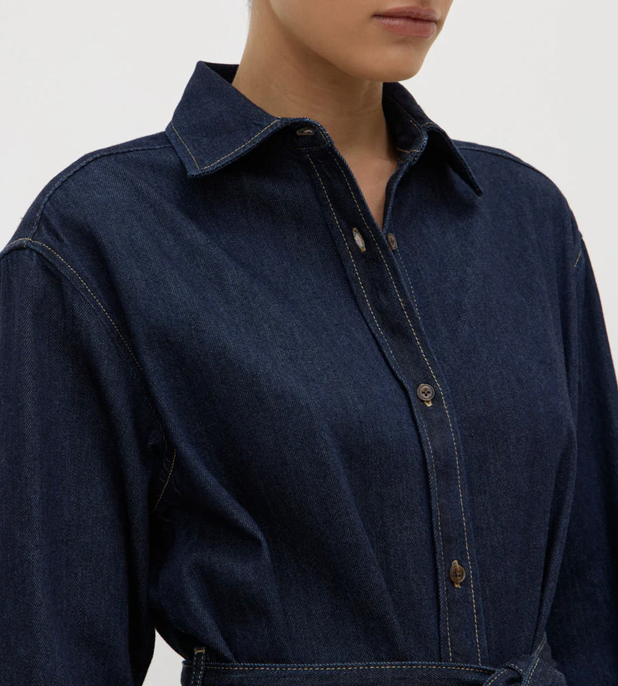 Navy blue denim shirt worn by a person on a light gray background