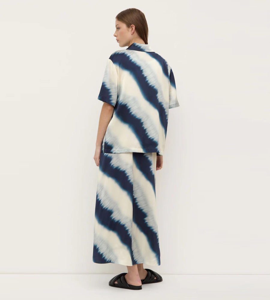 Person wearing a blue and white tie-dye outfit on a plain background