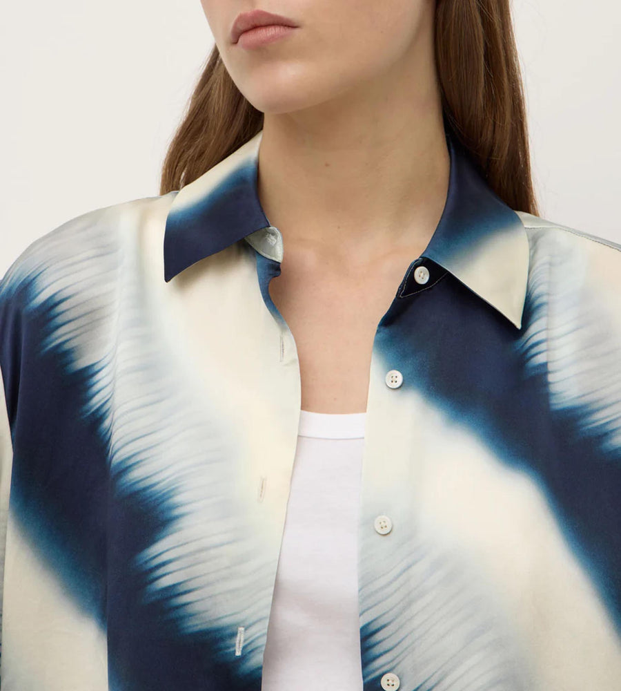 Person wearing a blue and white tie-dye shirt with a plain background