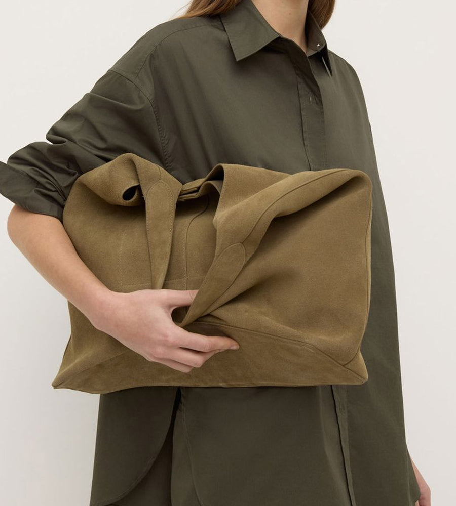 Person wearing a green shirt holding a brown fabric item against a white background