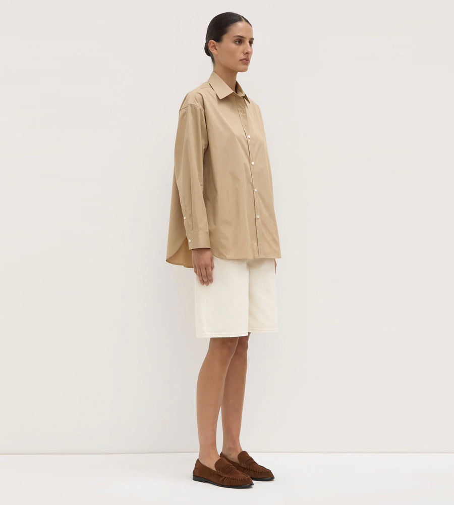 Woman wearing a beige shirt and white skirt against a white background