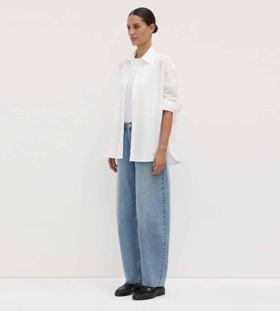 Person wearing a white shirt and light blue jeans against a white background