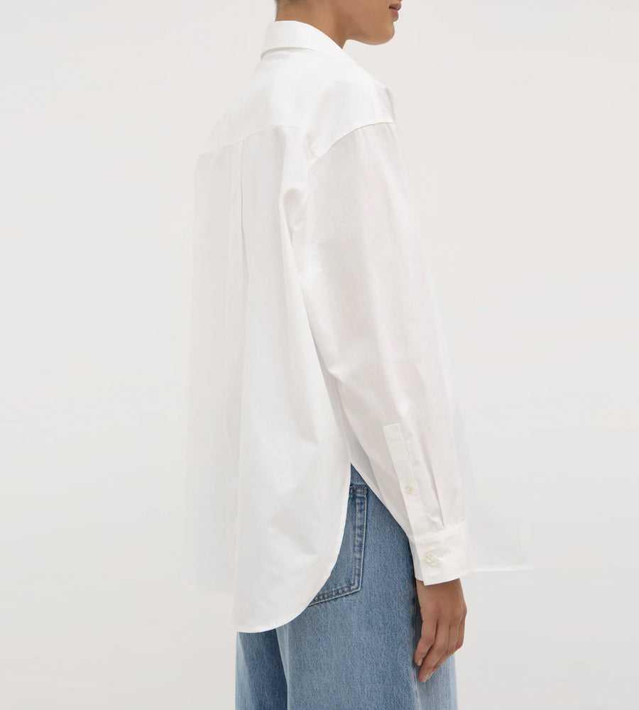 Person wearing a white shirt and blue jeans on a plain background