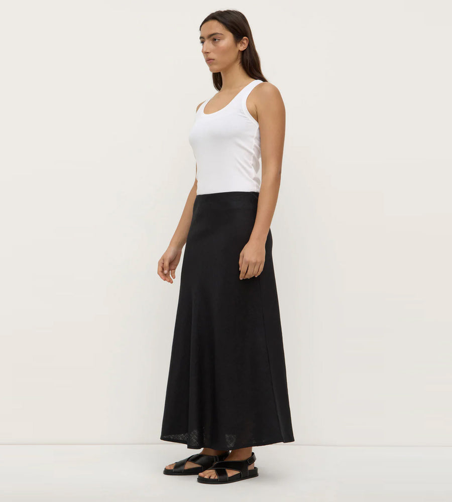 Woman wearing a white tank top and black long skirt on a white background