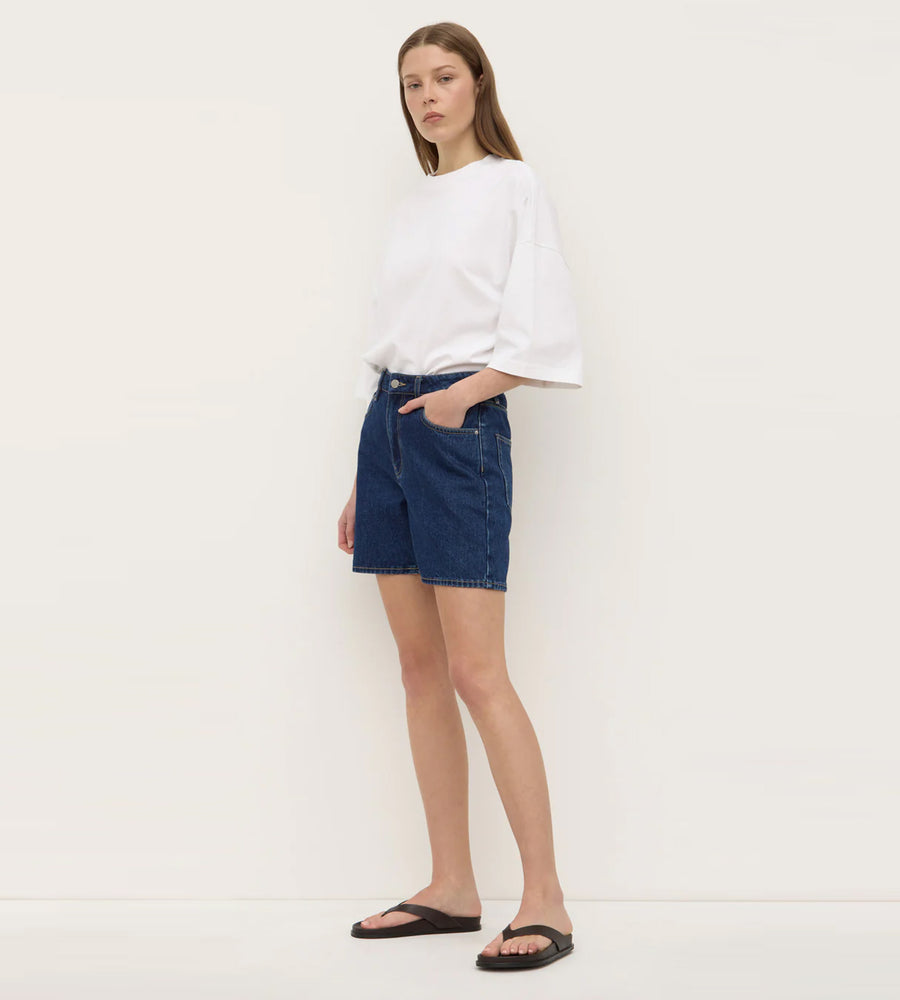 Woman wearing a white top and blue denim shorts on a white background