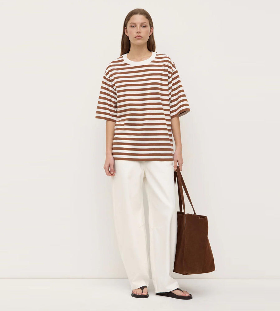 Woman wearing a striped shirt and holding a brown bag on a white background