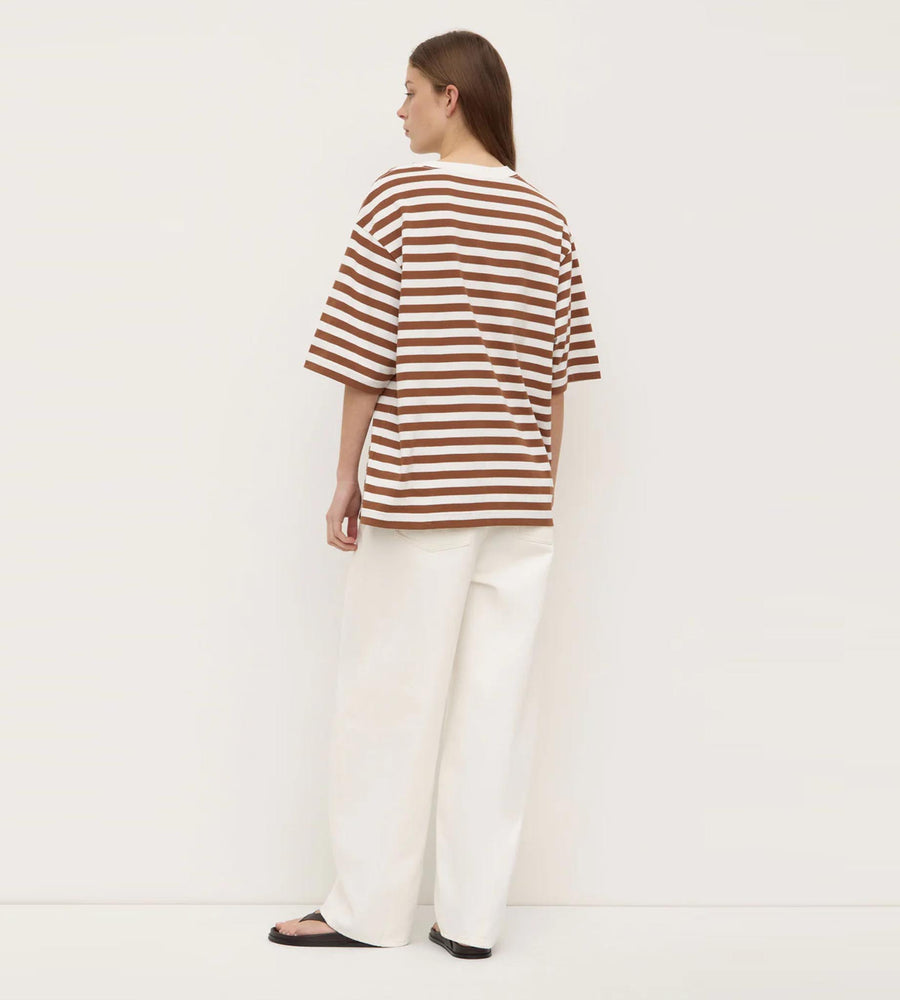Person wearing a brown and white striped shirt and white pants on a plain background