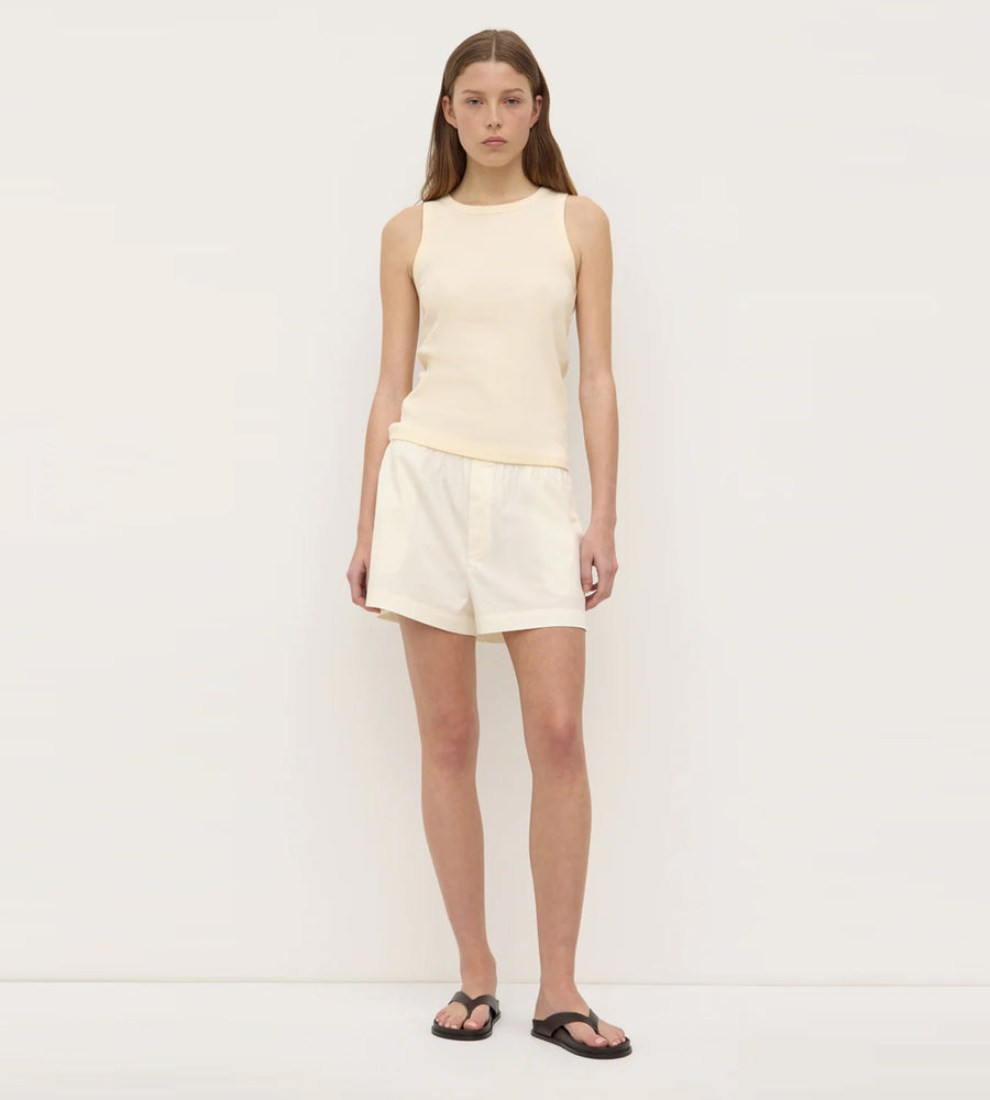 Woman wearing a light-colored sleeveless top and shorts on a white background