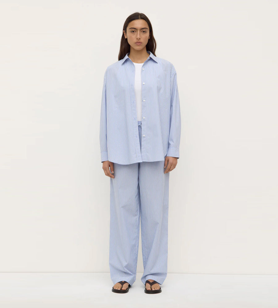 Person wearing a light blue striped pajama set on a white background