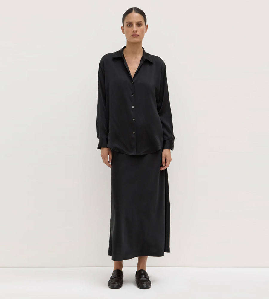 Person wearing a black outfit with a long skirt on a white background
