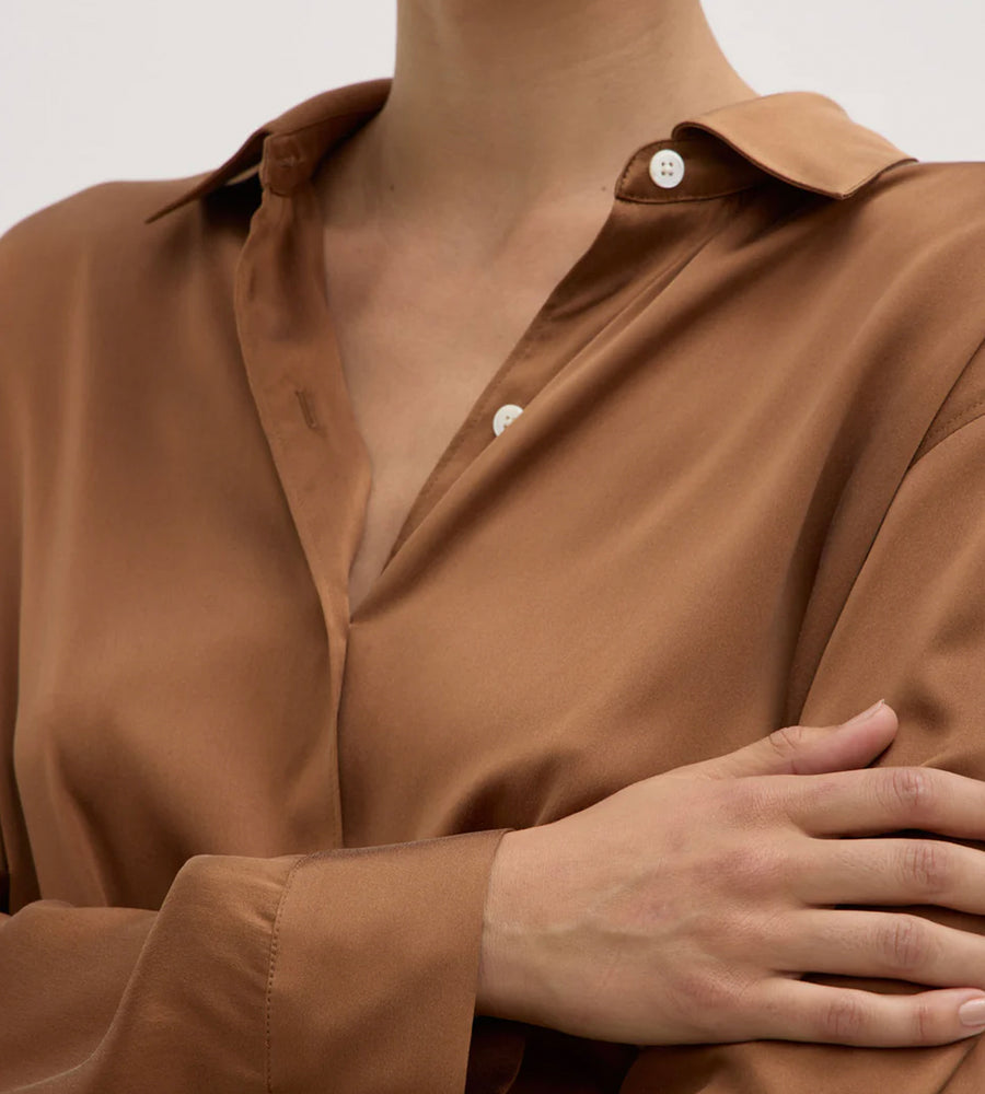 Close-up of a person wearing a brown shirt with a neutral background