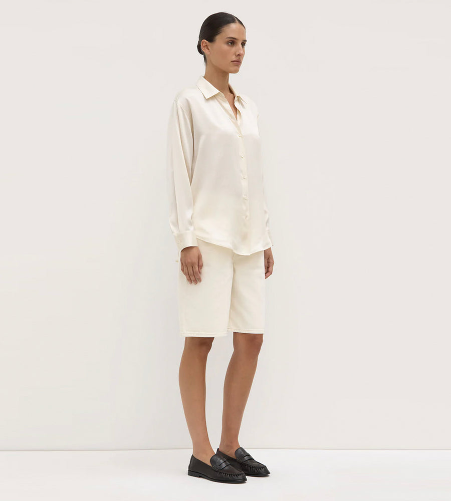 Person wearing a white shirt and skirt set against a plain background