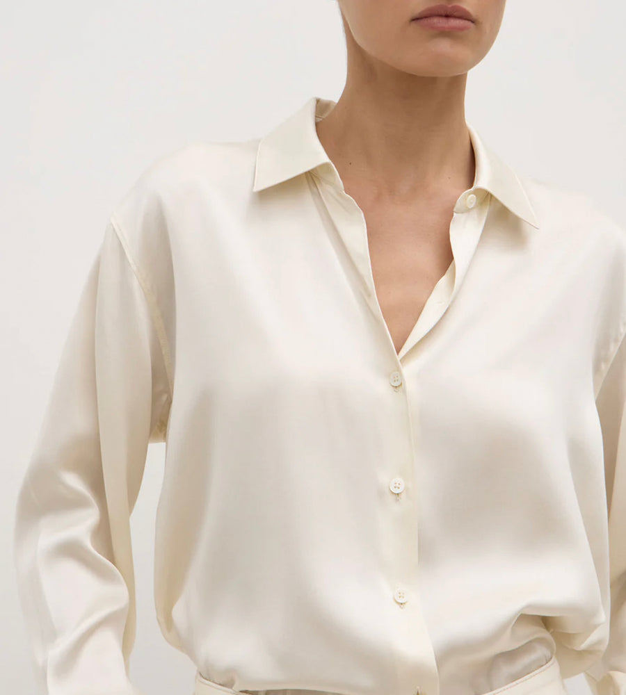 Close-up of a person wearing a cream-colored shirt against a white background