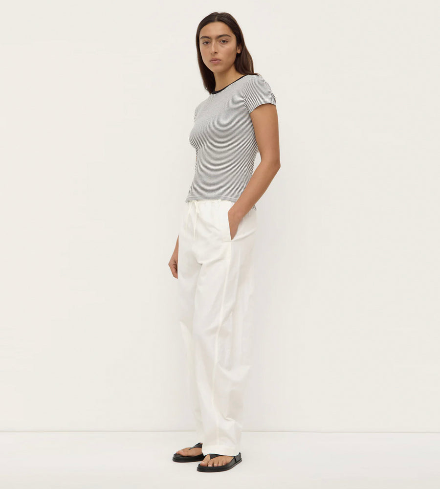 Woman wearing a gray top and white pants on a white background