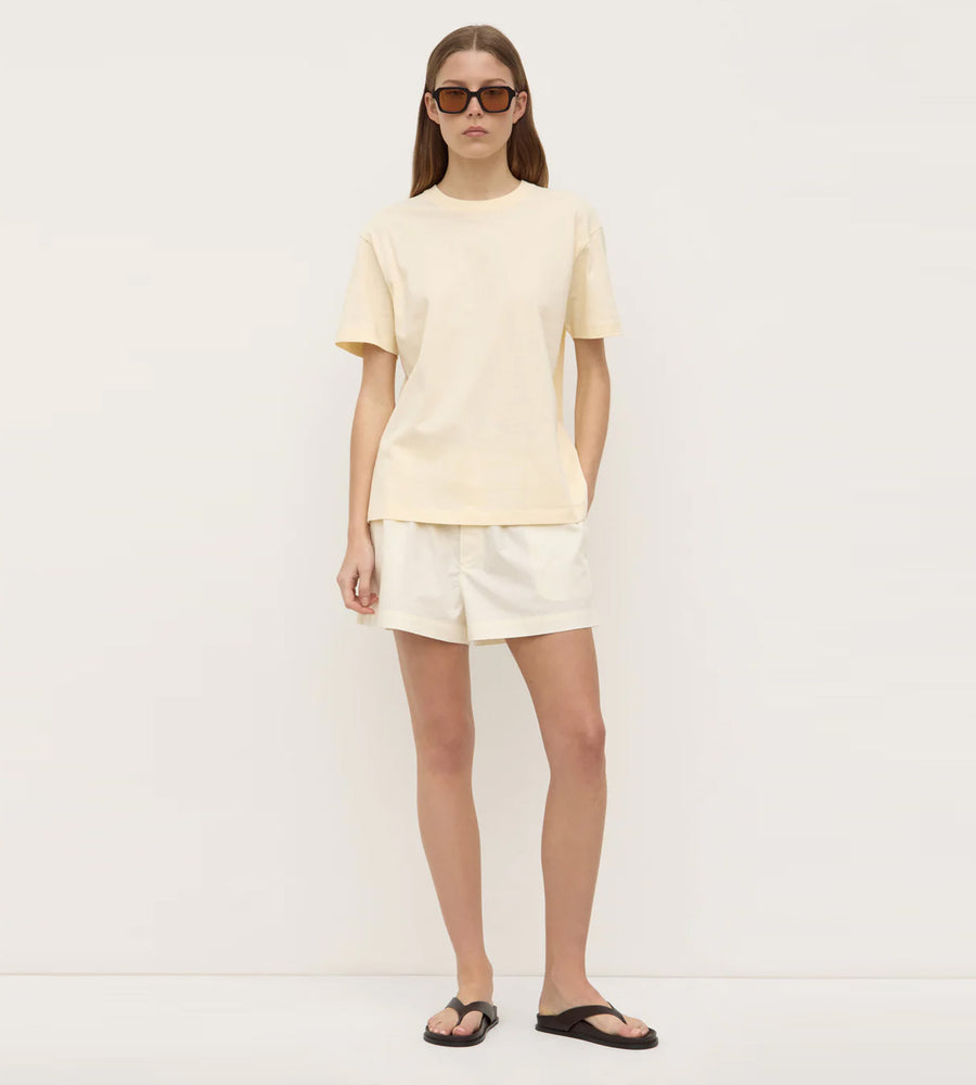 Person wearing a light yellow t-shirt and shorts on a white background