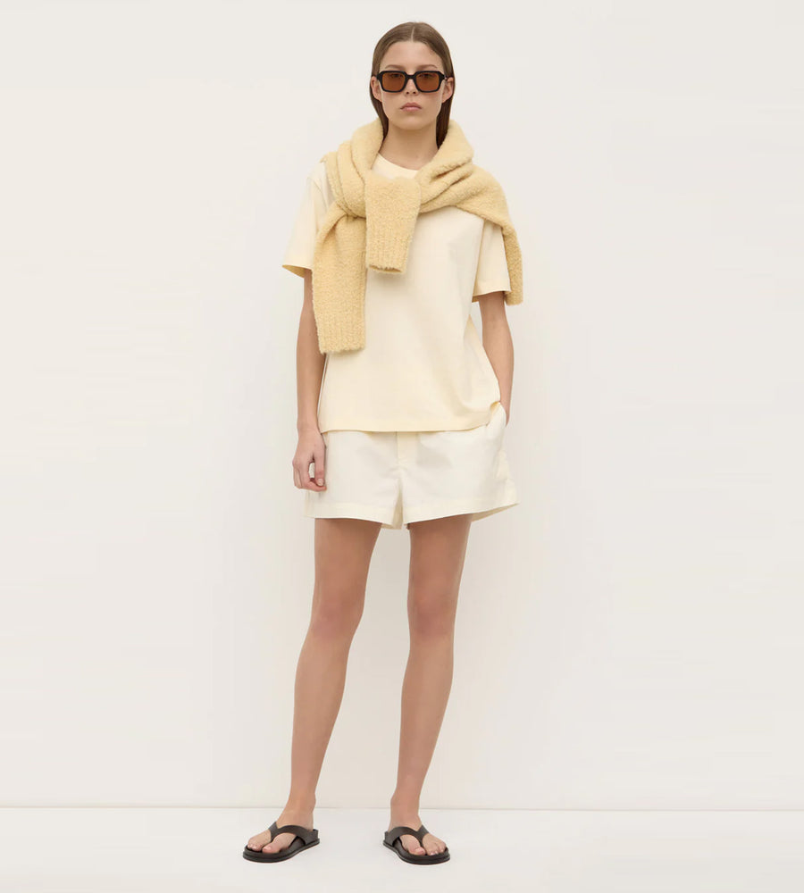Woman wearing a light yellow scarf and dress against a white background