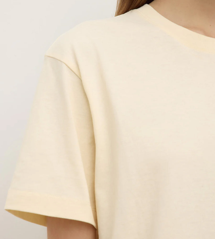 Close-up of a person wearing a light yellow dress against a plain background