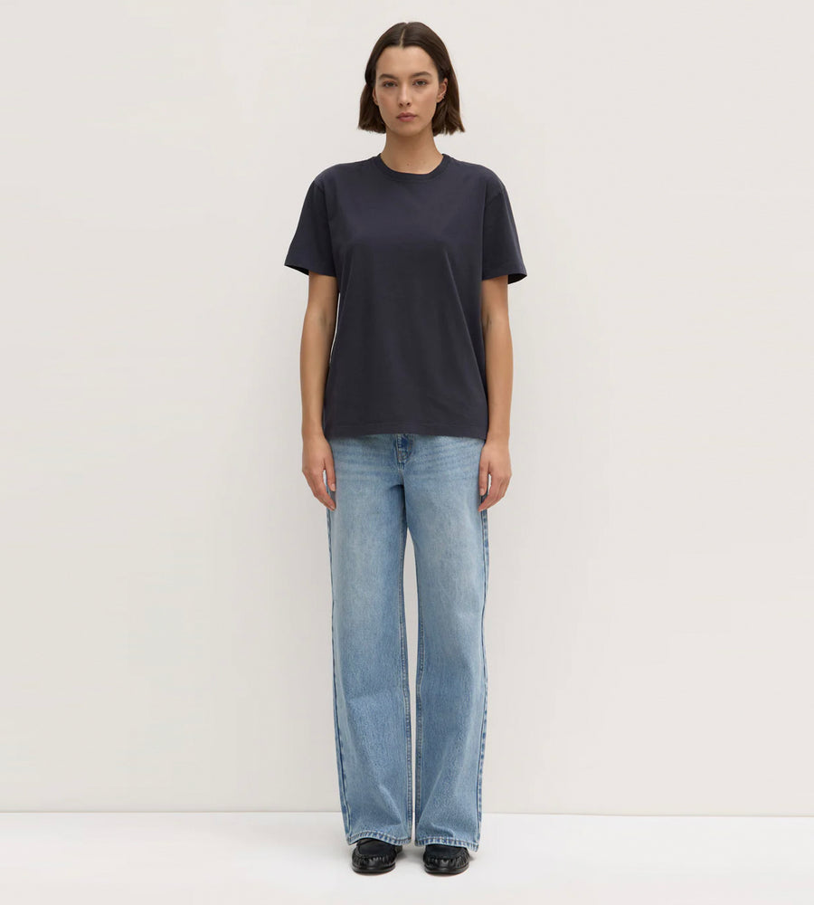 Person wearing a black t-shirt and light blue jeans on a white background