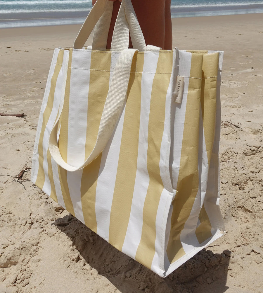 Striped yellow and white tote bag on a sandy beach